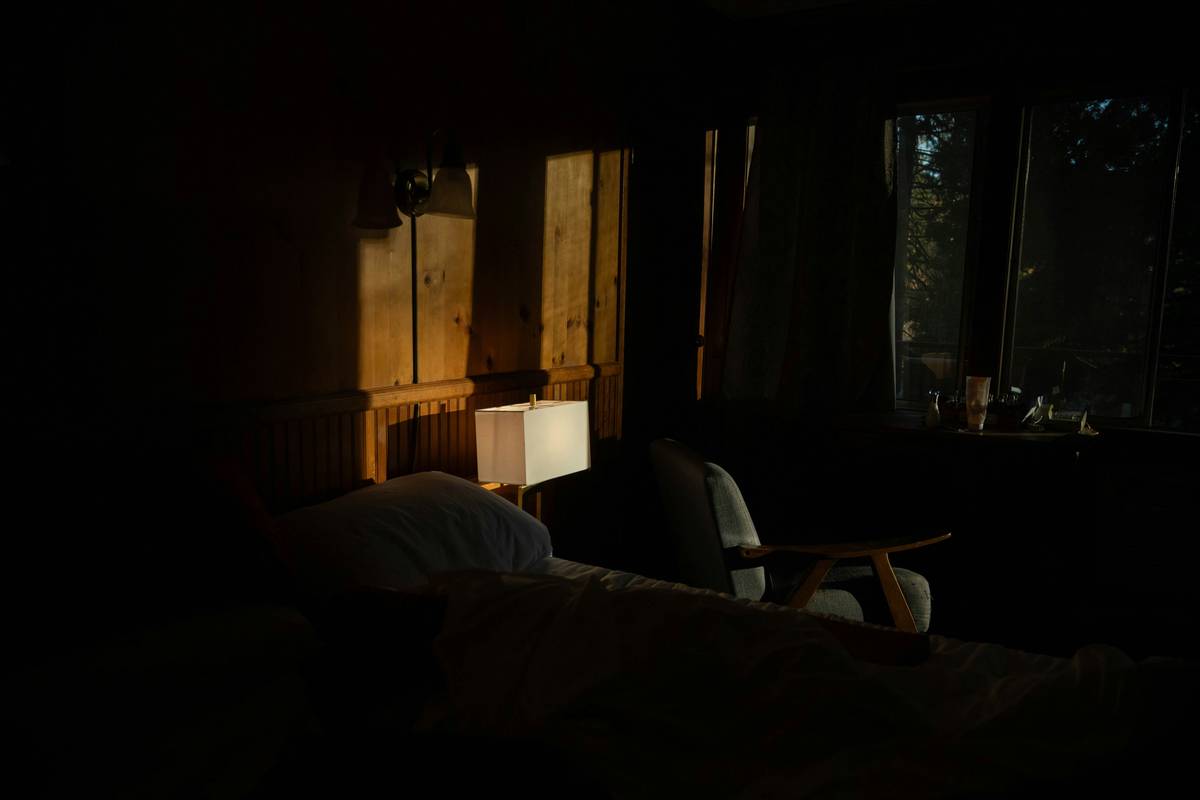 sleep hygiene tool insomnia relief tip: woman using a sleep mask and white noise machine in a dark, calm bedroom